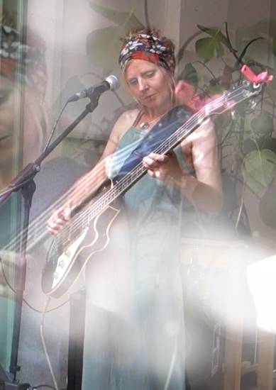 Frau steht auf der Straße und spielt E-Gitarre.