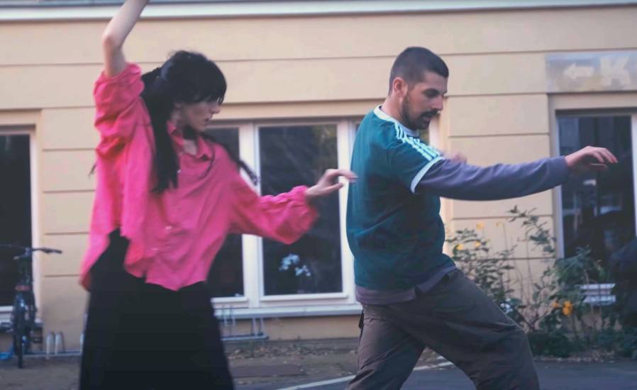 pop-up-exchange-2025 Eine Frau und ein Mann bewegen sich vor einer Häuserfassade tänzerisch