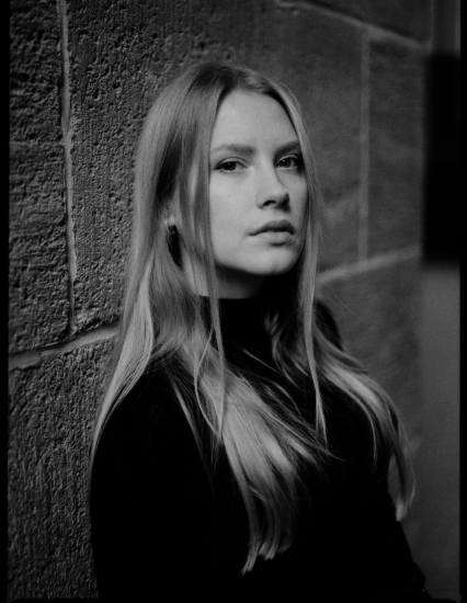 Ein schwarz-weiß Porträt-Foto der Singer-Songwriterin Vareshka. Sie blickt direkt und nachdenklich in die Kamera.