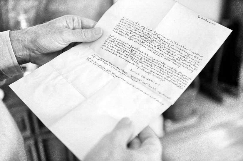 Schwarz-Weiß Foto von einem alten von Hand geschriebenen Brief den jemand in den Händen hält.